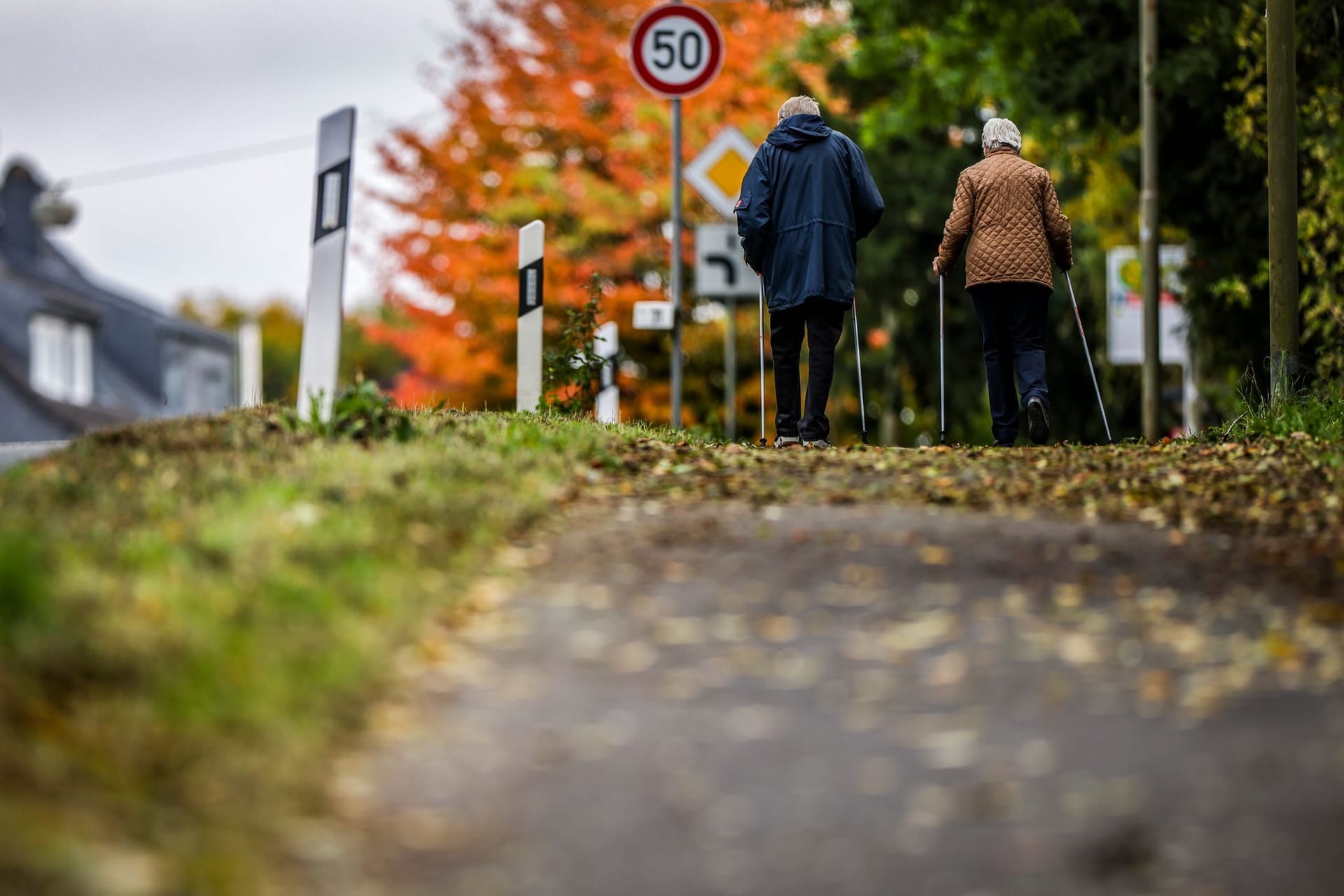 Zwei Senioren laufen auf einem mit Blättern bedeckten Weg