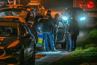 Polizisten führen in der Nacht einen mutmaßlichen Tatverdächtigen in Handschließen ab.