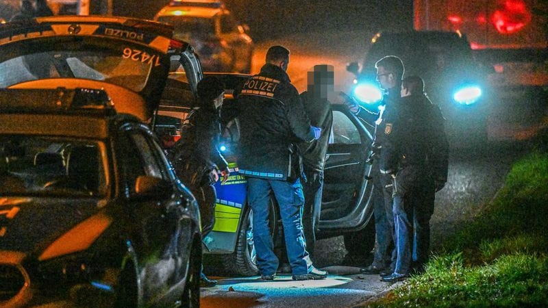 Polizisten führen in der Nacht einen mutmaßlichen Tatverdächtigen in Handschließen ab.