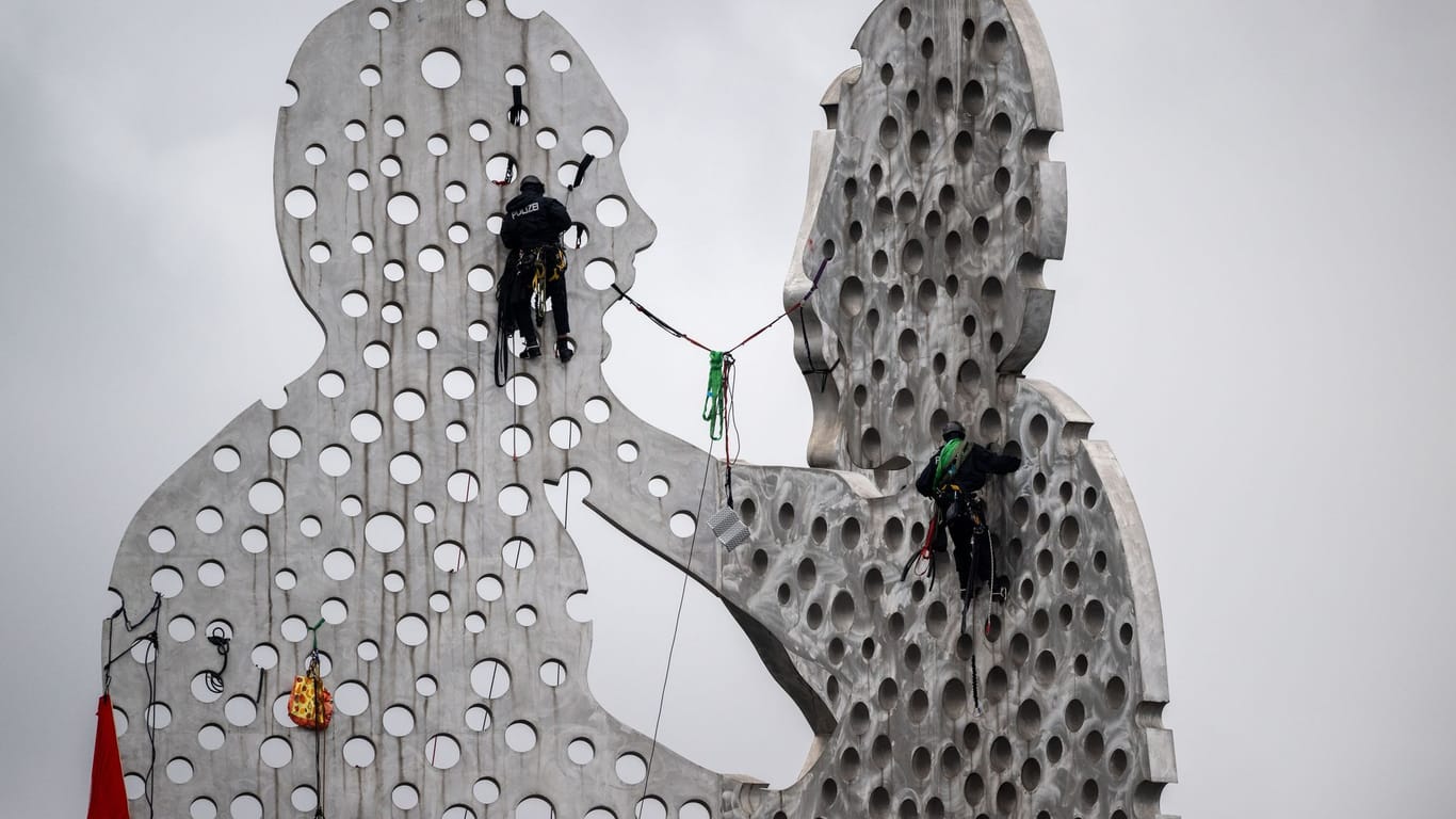 Aktivisten klettern auf Skulptur Molecule Man in der Spree