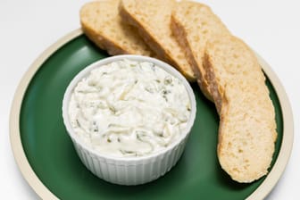 Traditional homemade greek yogurt sauce Tzatziki, tarator in white bowl, grated cucumbers, sour cream yogurt,olive oil,garlic,herbs on plate with sliced bread, white background.Horizontal