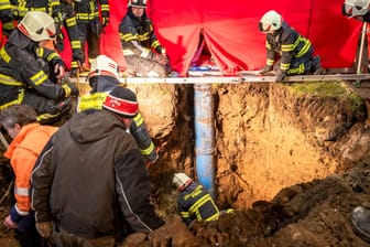 Die Feuerwehr gräbt den Weg frei: Ein kleiner Junge war durch eine Abdeckung auf einer Wiese drei Meter tief in ein Rohr gestürzt.