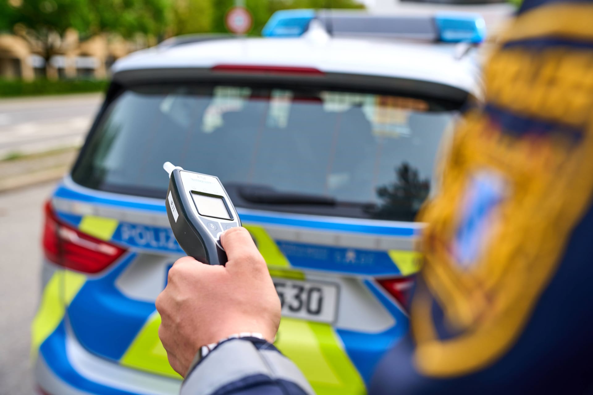 Ein Polizist hält ein Atemalkohol-Testgerät in der Hand (Archivbild): Der Busfahrer musste seinen Führerschein abgeben.