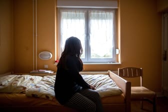 Eine Frau sitzt in einem Frauenhaus auf einem Bett (Archivbild). Eine 28-jährige Türkin ist mit ihren beiden Kindern abgeschoben worden.