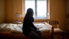 Eine Frau sitzt in einem Frauenhaus auf einem Bett (Archivbild). Eine 28-jährige Türkin ist mit ihren beiden Kindern abgeschoben worden.