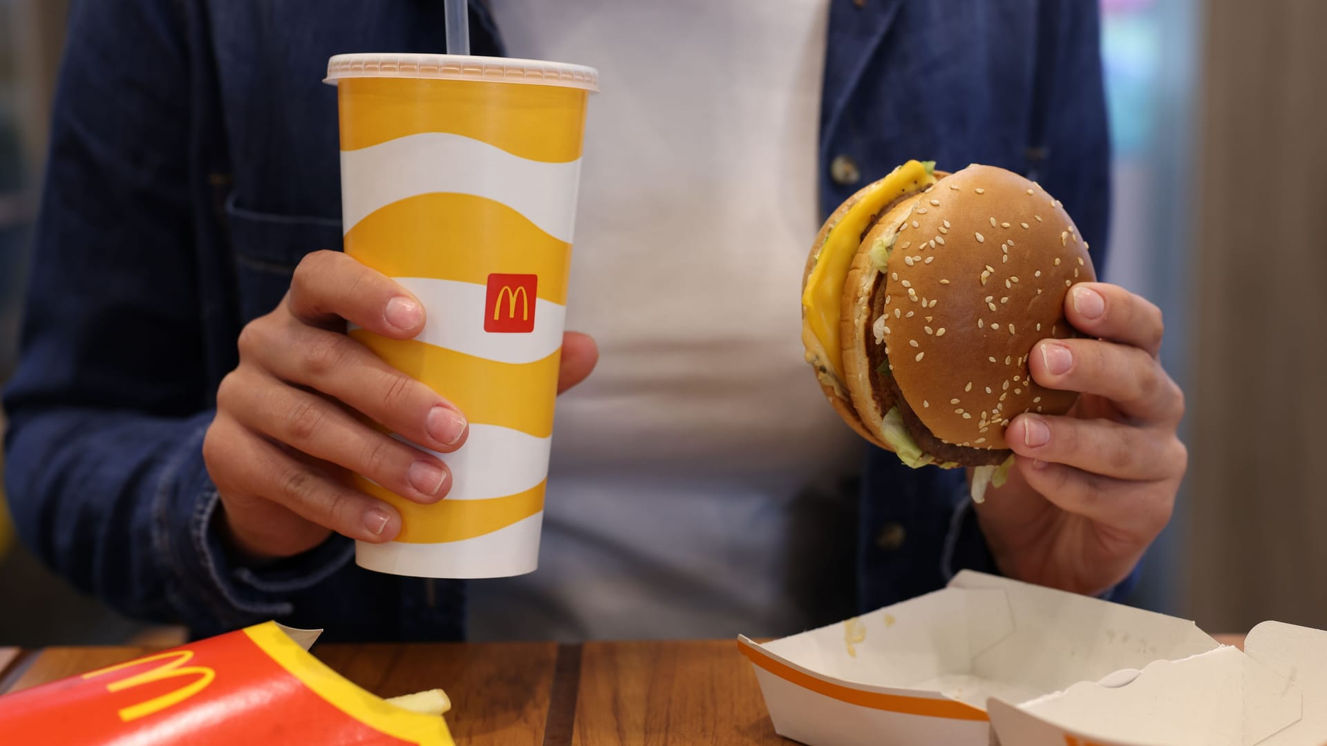 Lviv, Ukraine - October 9, 2023: Woman with McDonald's menu at wooden table in restaurant, closeup