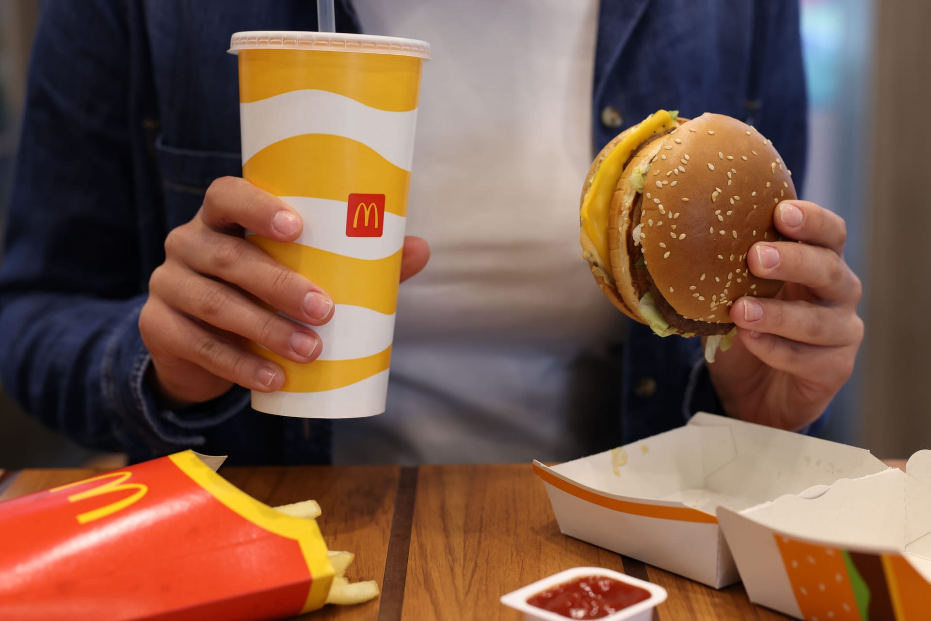 Lviv, Ukraine - October 9, 2023: Woman with McDonald's menu at wooden table in restaurant, closeup