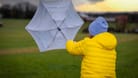 Eine Frau kämpft mit ihrem Regenschirm gegen den Sturm an. (Symbolfoto)