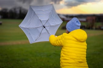 Eine Frau kämpft mit ihrem Regenschirm gegen den Sturm an. (Symbolfoto)