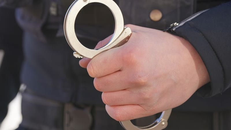 Ein Polizist hält Handschellen in der Hand (Symbolbild): Die Staatsanwaltschaft klagt einen 23-Jährigen wegen versuchten Mordes und Vergewaltigung an.