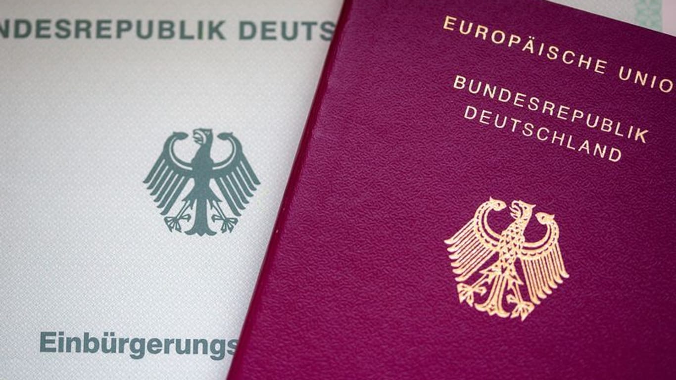 Eine Einbürgerungsurkunde der Bundesrepublik Deutschland (l) und ein deutscher Reisepass liegen auf einem Tisch.