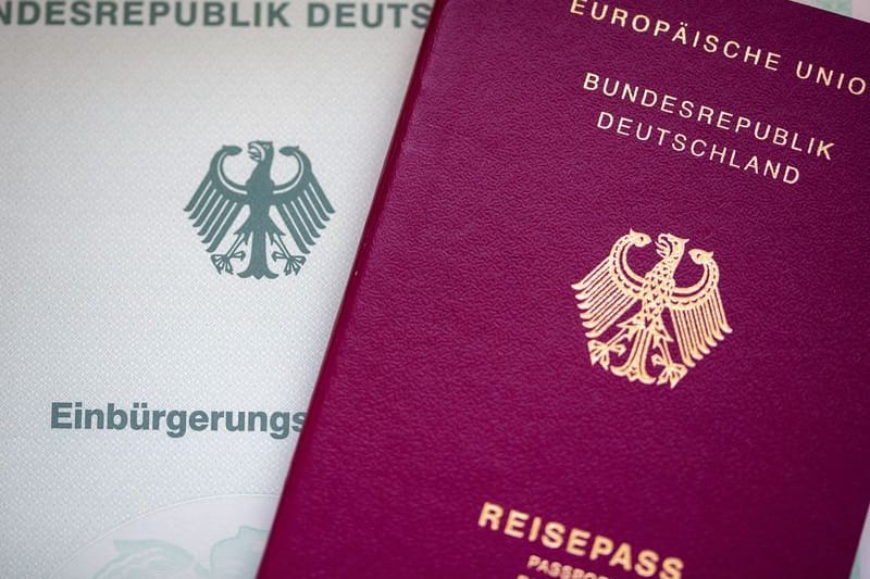 Eine Einbürgerungsurkunde der Bundesrepublik Deutschland (l) und ein deutscher Reisepass liegen auf einem Tisch.