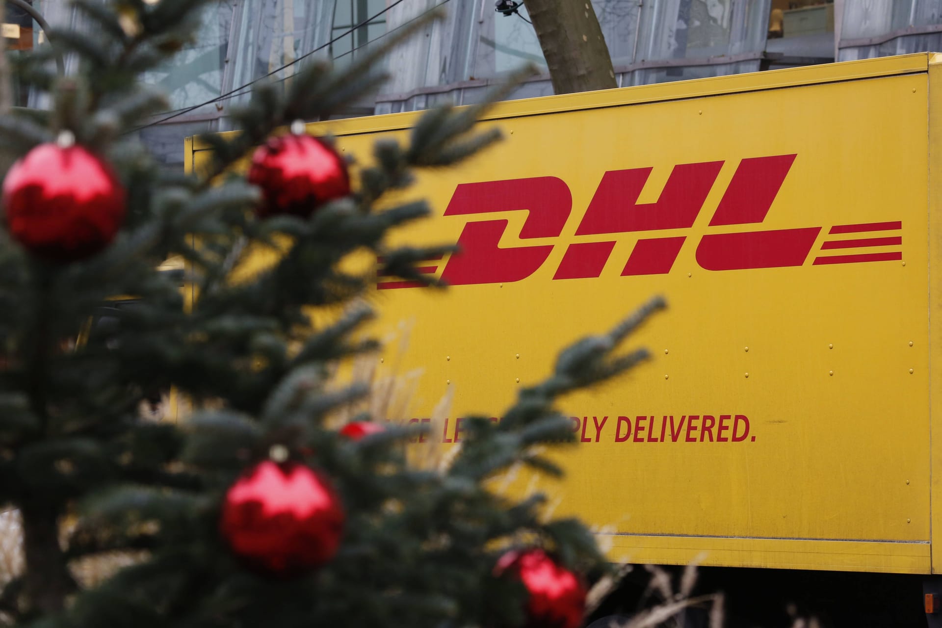 DHL Logo auf einem LKW und ein Weihnachtsbaum im Vordergrund (Symbolbild): Die DHL-Lieferanten haben in der Vorweihnachtszeit alle Hände voll zutun.