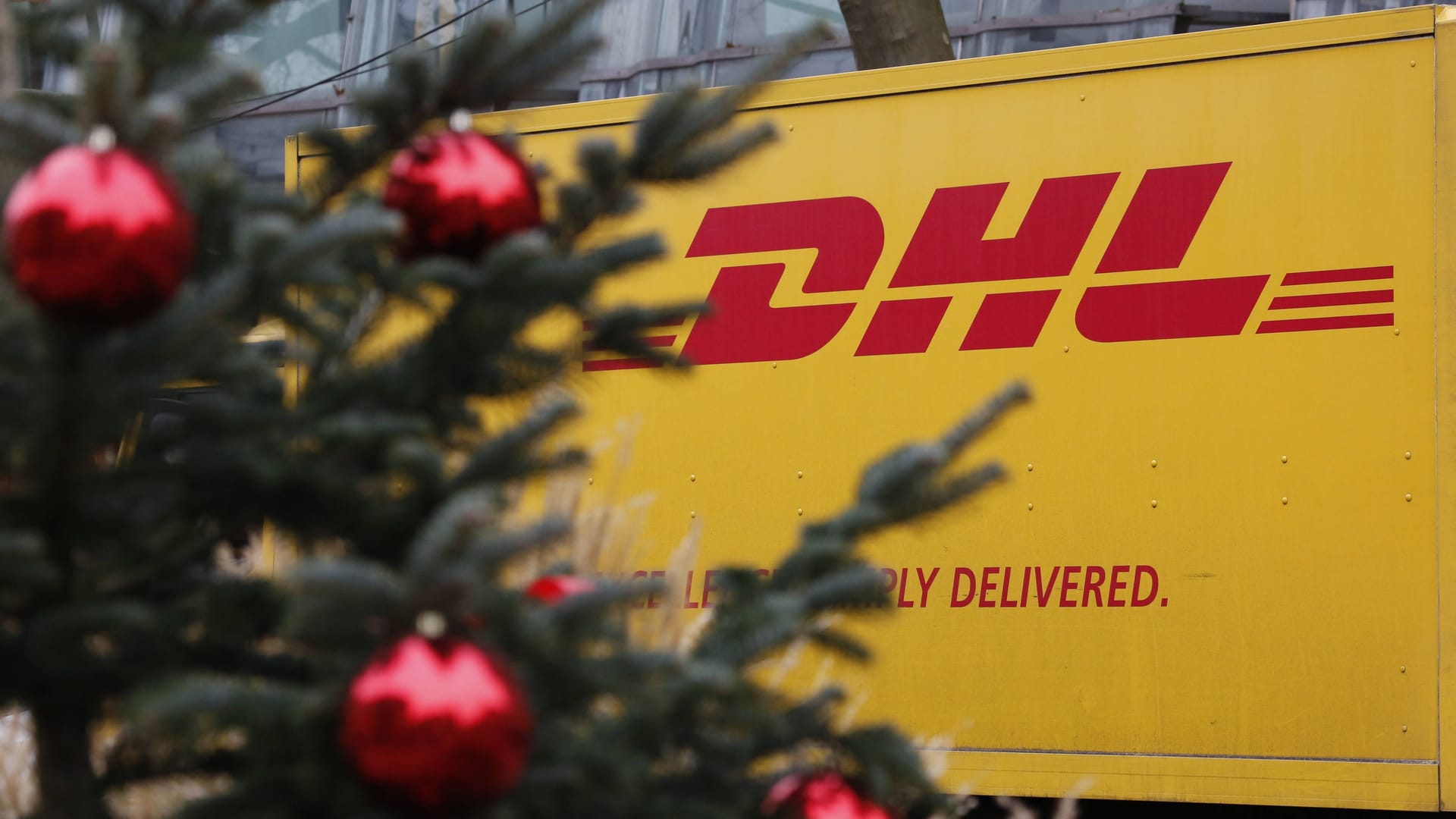 DHL Logo auf einem LKW und ein Weihnachtsbaum im Vordergrund (Symbolbild): Die DHL-Lieferanten haben in der Vorweihnachtszeit alle Hände voll zutun.