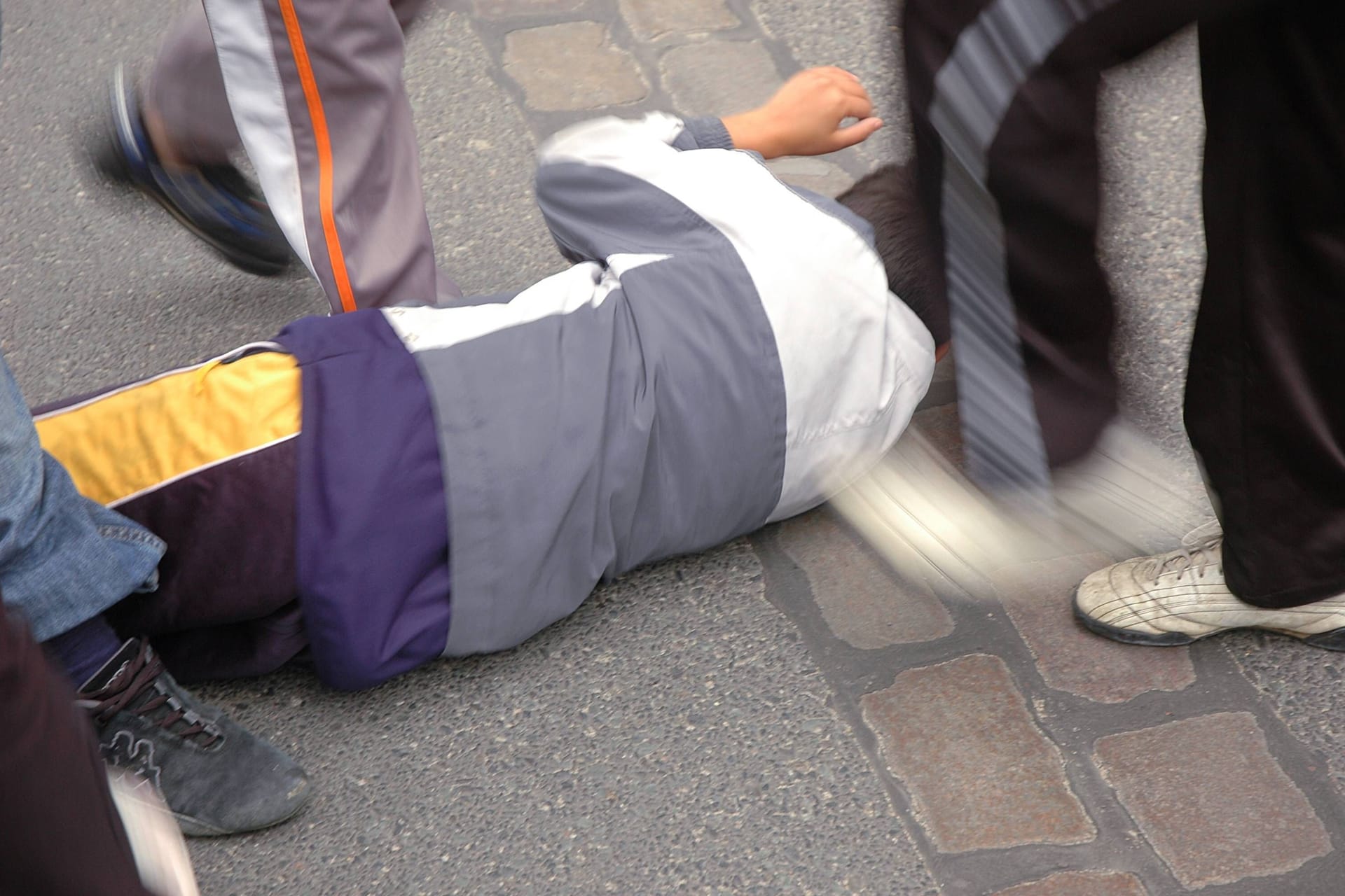 Eine am Boden liegende Person wird von mehreren Personen getreten (Symbolbild): In Essen ist ein Mann nach einem Diebstahl von vier Personen angegriffen worden.