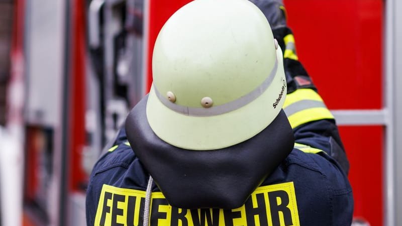 Ein Feuerwehrmann holt eine Leiter vom Dach eines Einsatzfahrzeugs (Symbolbild): 40 Einsatzkräfte rückten am Freitag in Hürth aus.