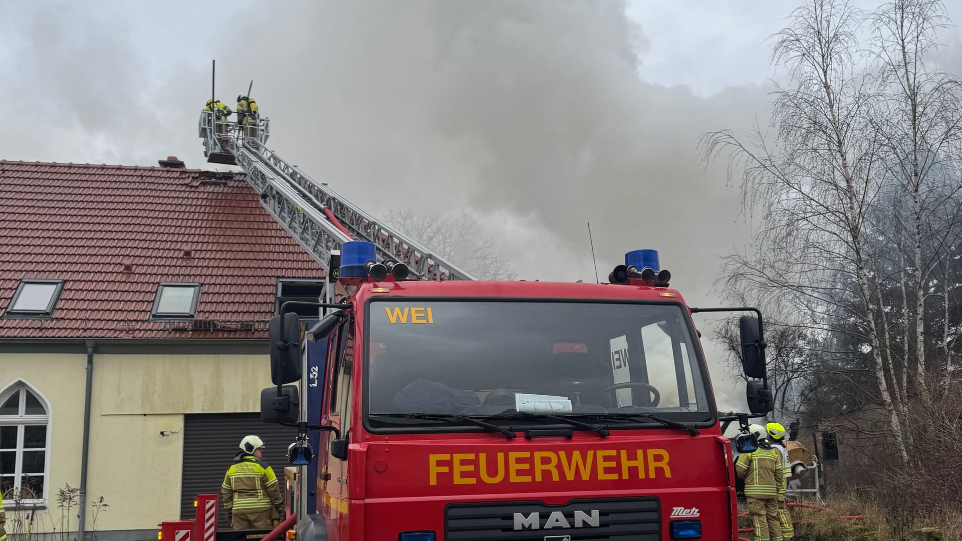 Die Feuerwehr löscht mit einer Drehleiter: Der Einsatz wird voraussichtlich noch bis in den Nachmittag andauern.