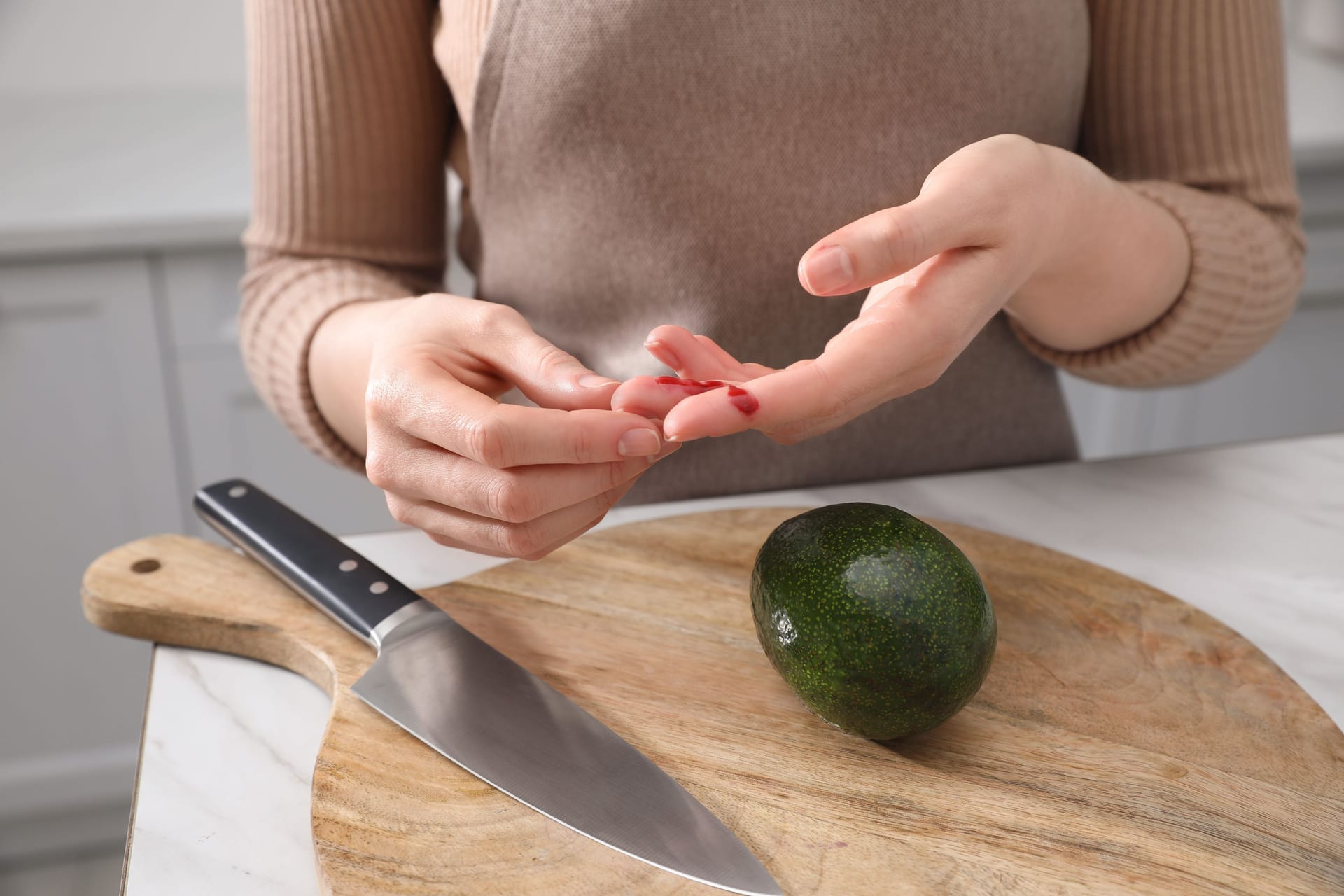 Eine Frau hat sich beim Schneiden einer Avocado in den Finger geschnitten.