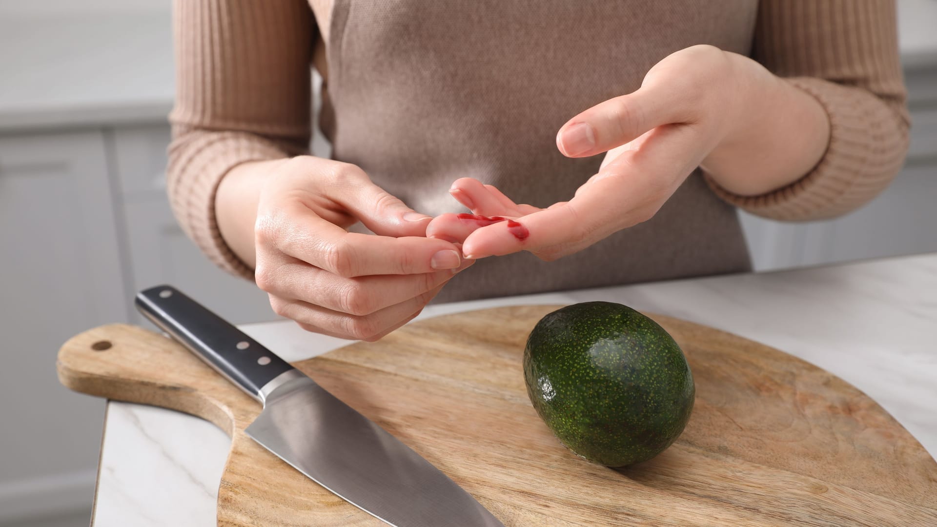 Eine Frau hat sich beim Schneiden einer Avocado in den Finger geschnitten.