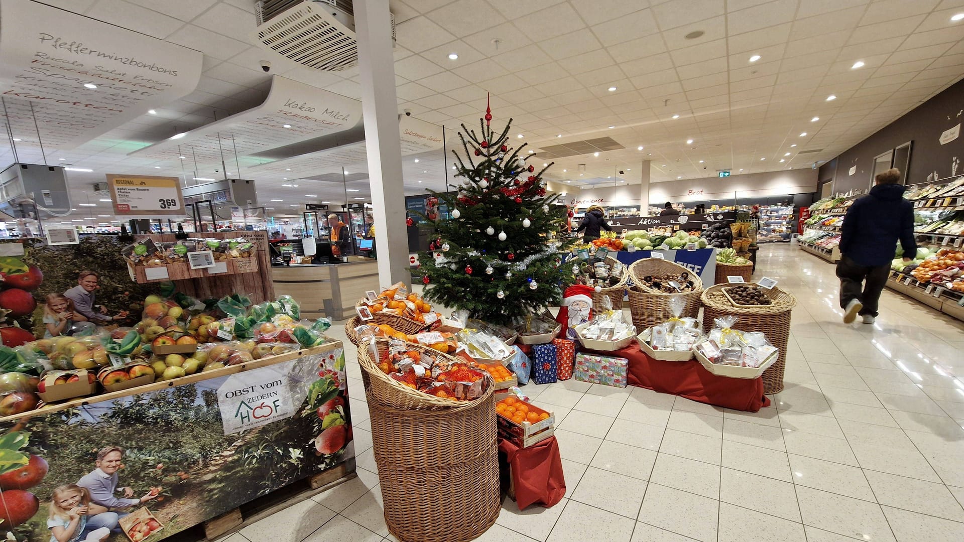 Eingangsbereich eines Supermarktes mit Weihnachtsbaum: An Heiligabend schließen die meisten Geschäfte in Köln um 14 Uhr. Doch es gibt Ausnahmen.