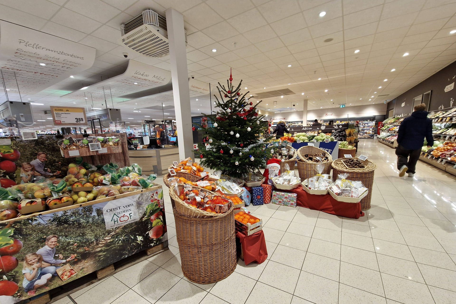 Eingangsbereich eines Supermarktes mit Weihnachtsbaum: An Heiligabend schließen die meisten Geschäfte in Köln um 14 Uhr. Doch es gibt Ausnahmen.