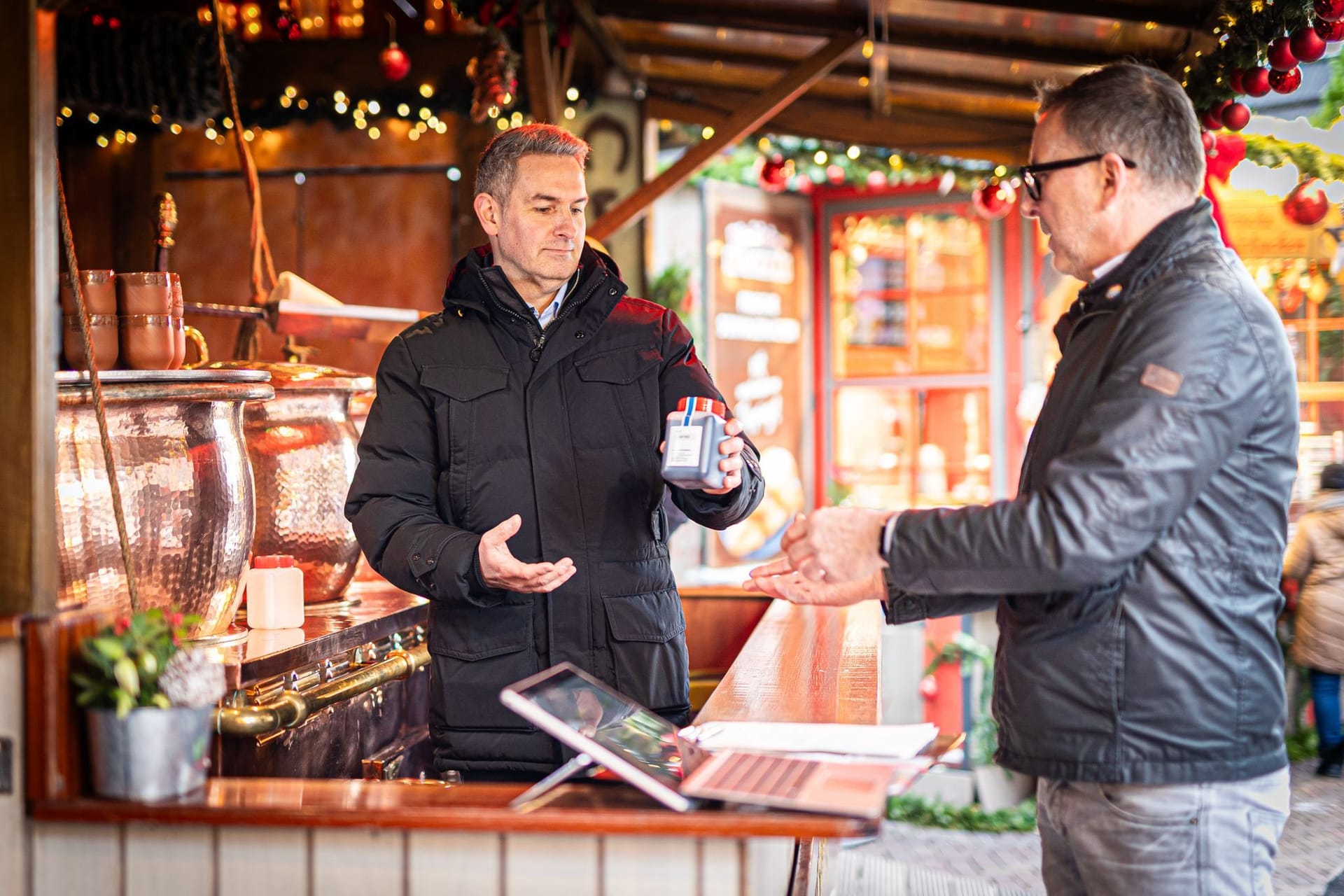 Weinkontrolleur Moritz Kröning (l) übergibt auf einem Weihnachtsmarkt die Probe einer Feuerzangenbowle an Lebensmittelkontrolleur Thomas Rautenberg.