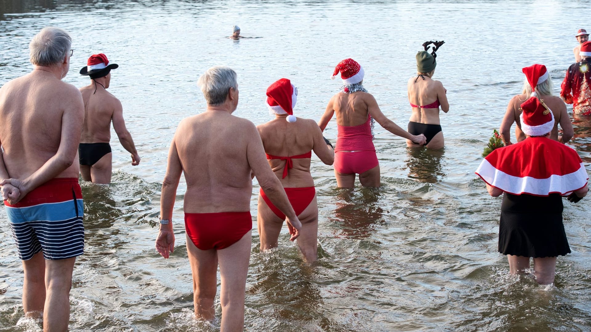 25.12.2024, Berlin: Mitglieder des Vereins «Berliner Seehunde» gehen beim Weihnachtsbaden in den Orankesee. Seit über dreißig Jahren kommen die Berliner Seehunde immer sonntag von Oktober bis April an den Orankesee zum Eisbaden - Höhepunkte sind das Weihnachtsbaden und der Eisbaderfasching.