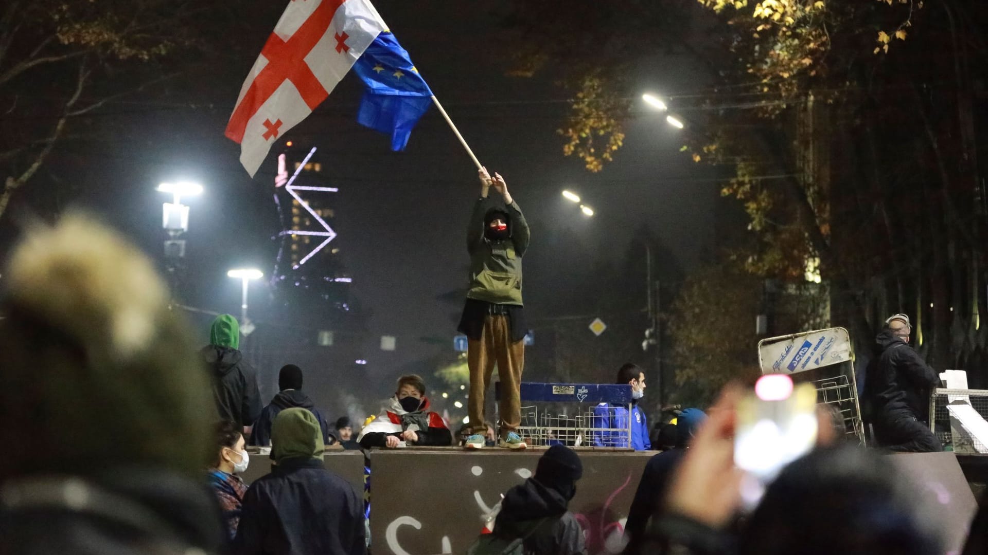 Ein Demonstrant steht mit georgischen National- und EU-Flaggen während einer Kundgebung vor dem Parlamentsgebäude.