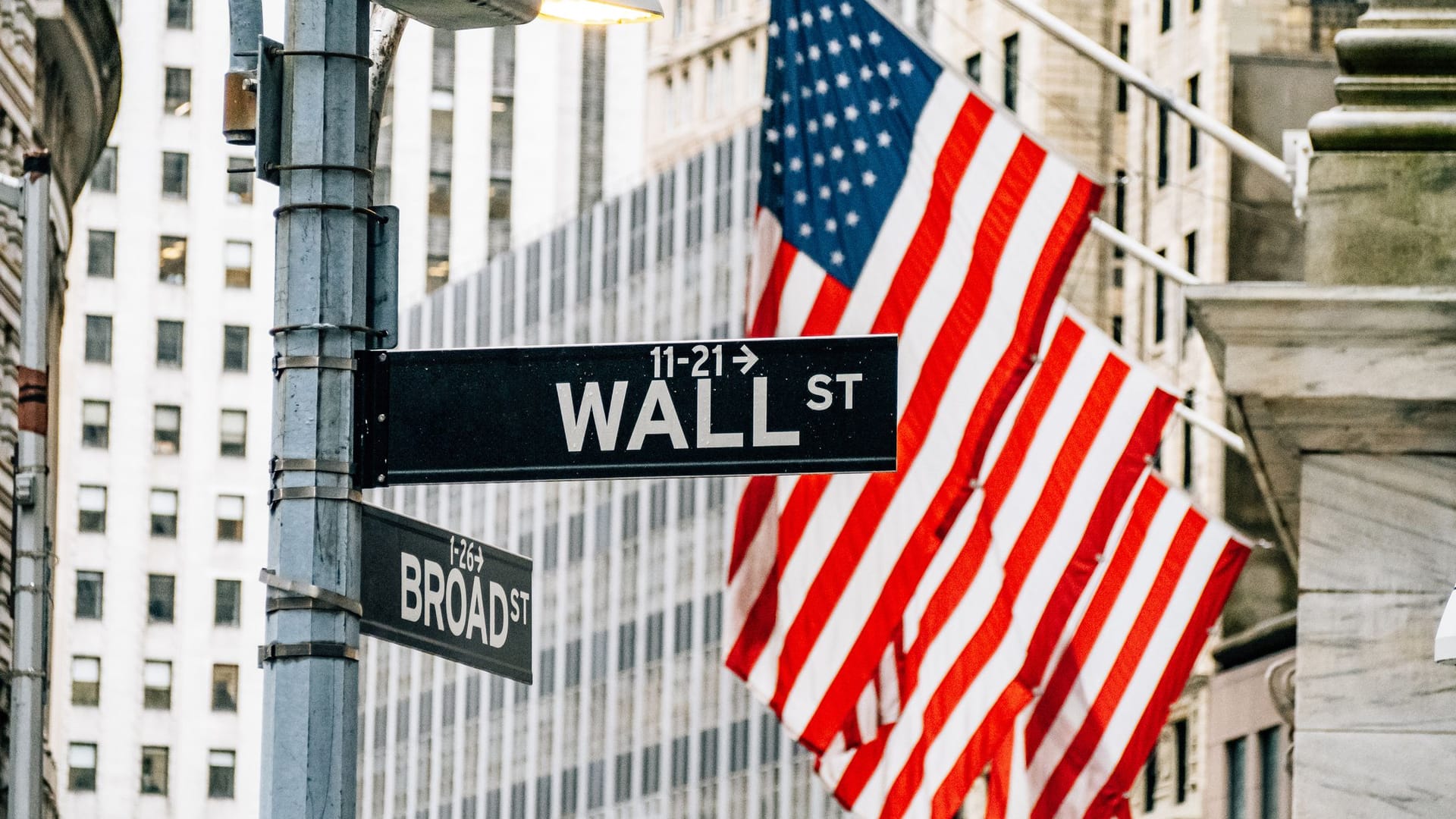 Wall Street in New York mit US-Flagge im Hintergrund