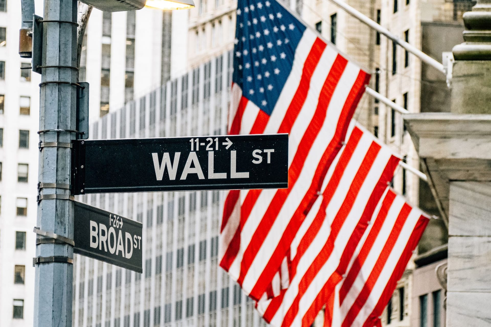 Wall Street in New York mit US-Flagge im Hintergrund