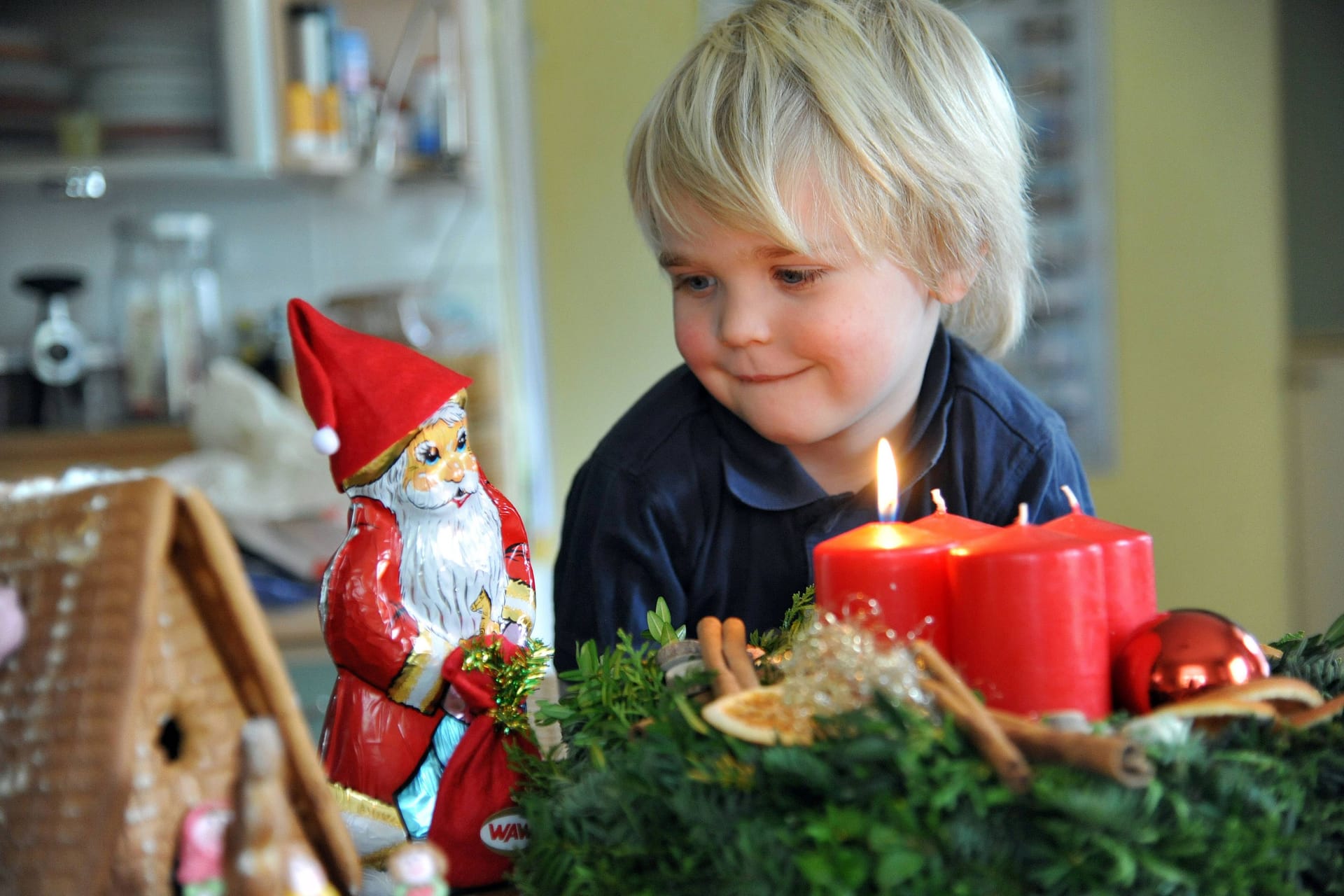 Ein Junge schaut auf einen Adventskranz mit brennender Kerze: Die Idee entstand vor fast zwei Jahrhunderten in Hamburg.