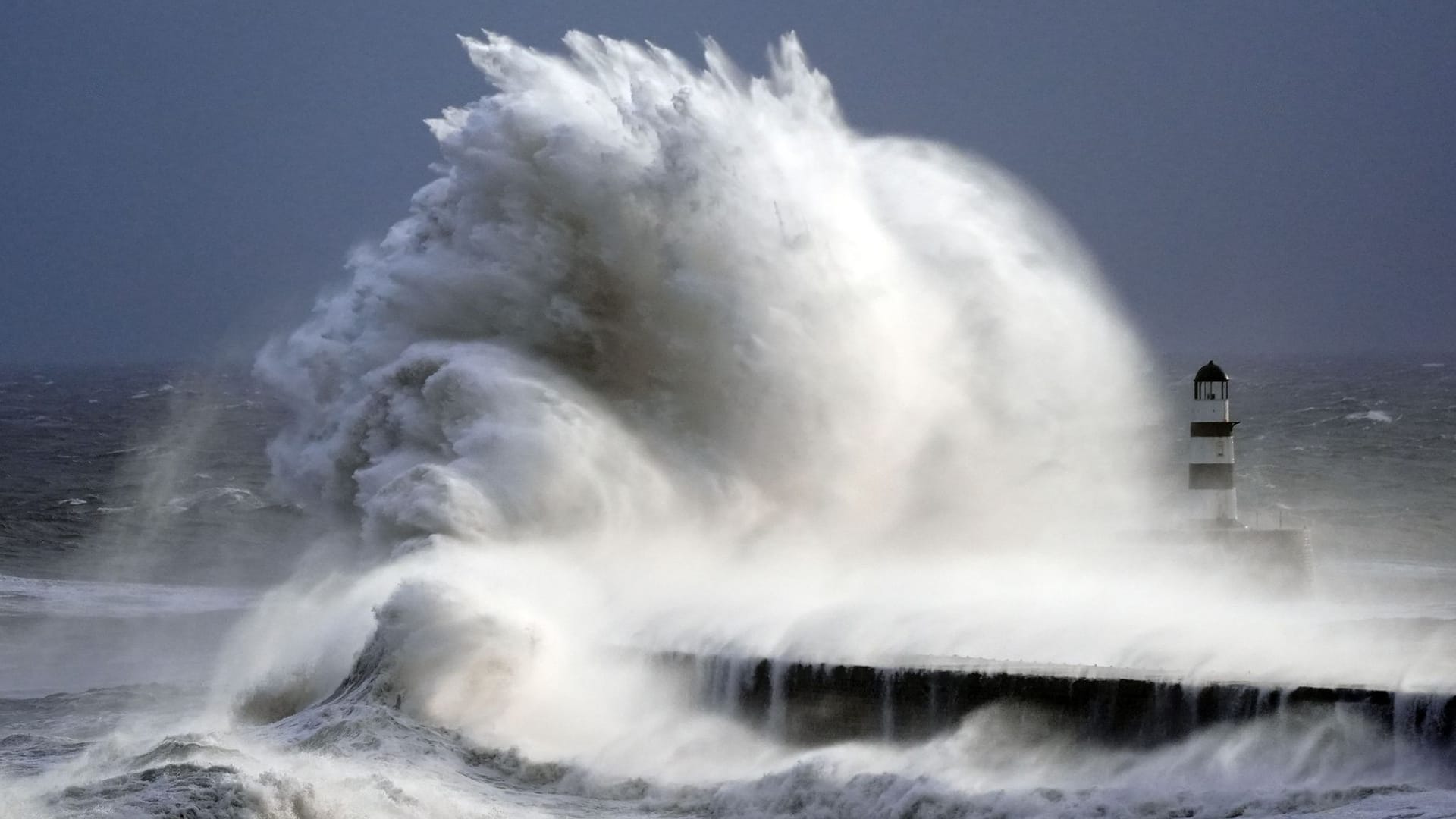 Wellen schlagen gegen einen Leuchtturm (Symbolfoto): Die Menschen im Norden müssen sich auf stürmische Feiertage einstellen.