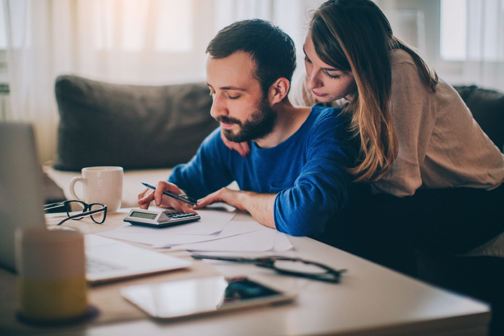 Paar sitzt im Wohnzimmer und checkt seine Finanzen