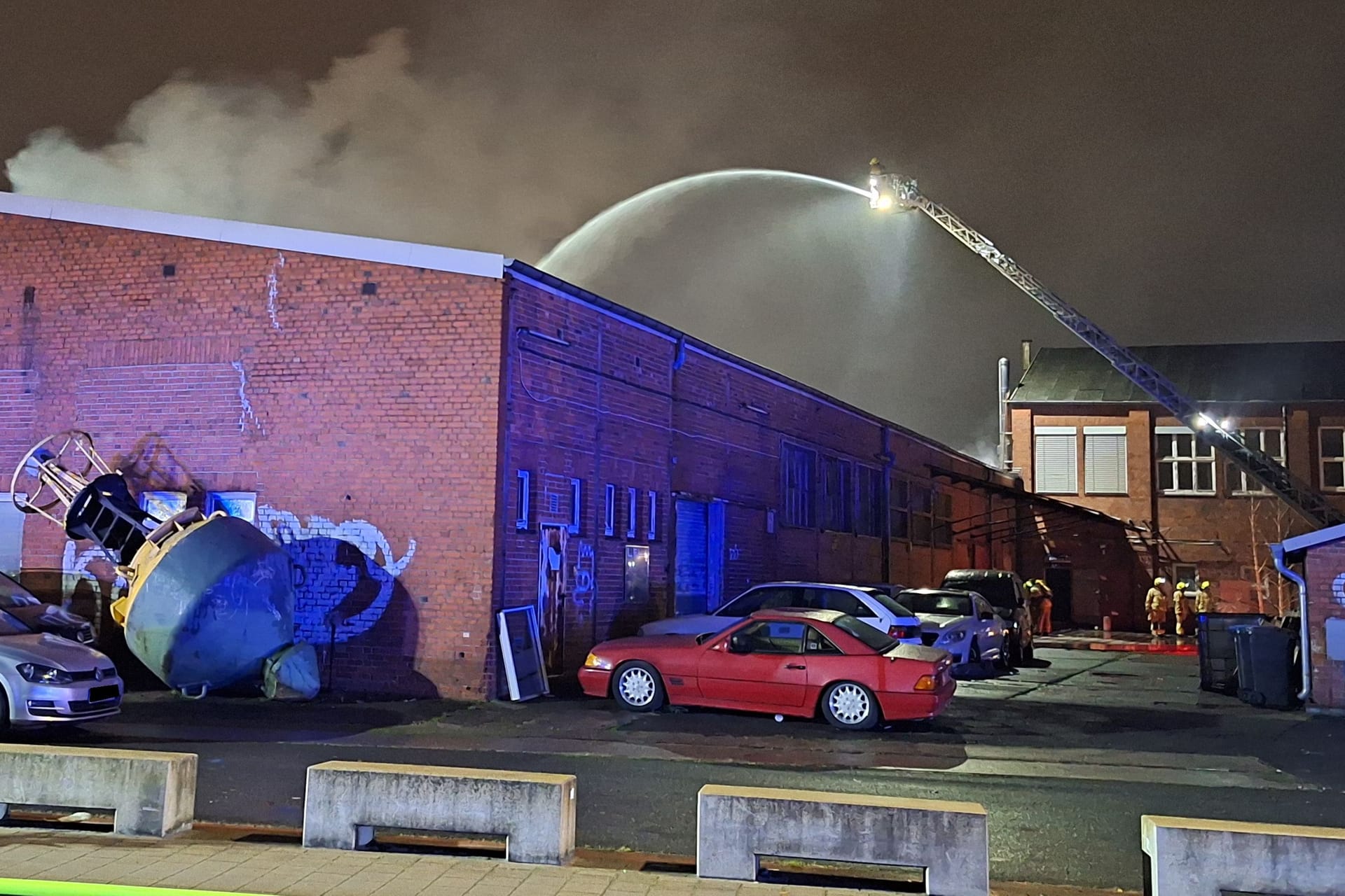 Flammen schlagen aus dem Dach einer Lagerhalle und Autowerkstatt.