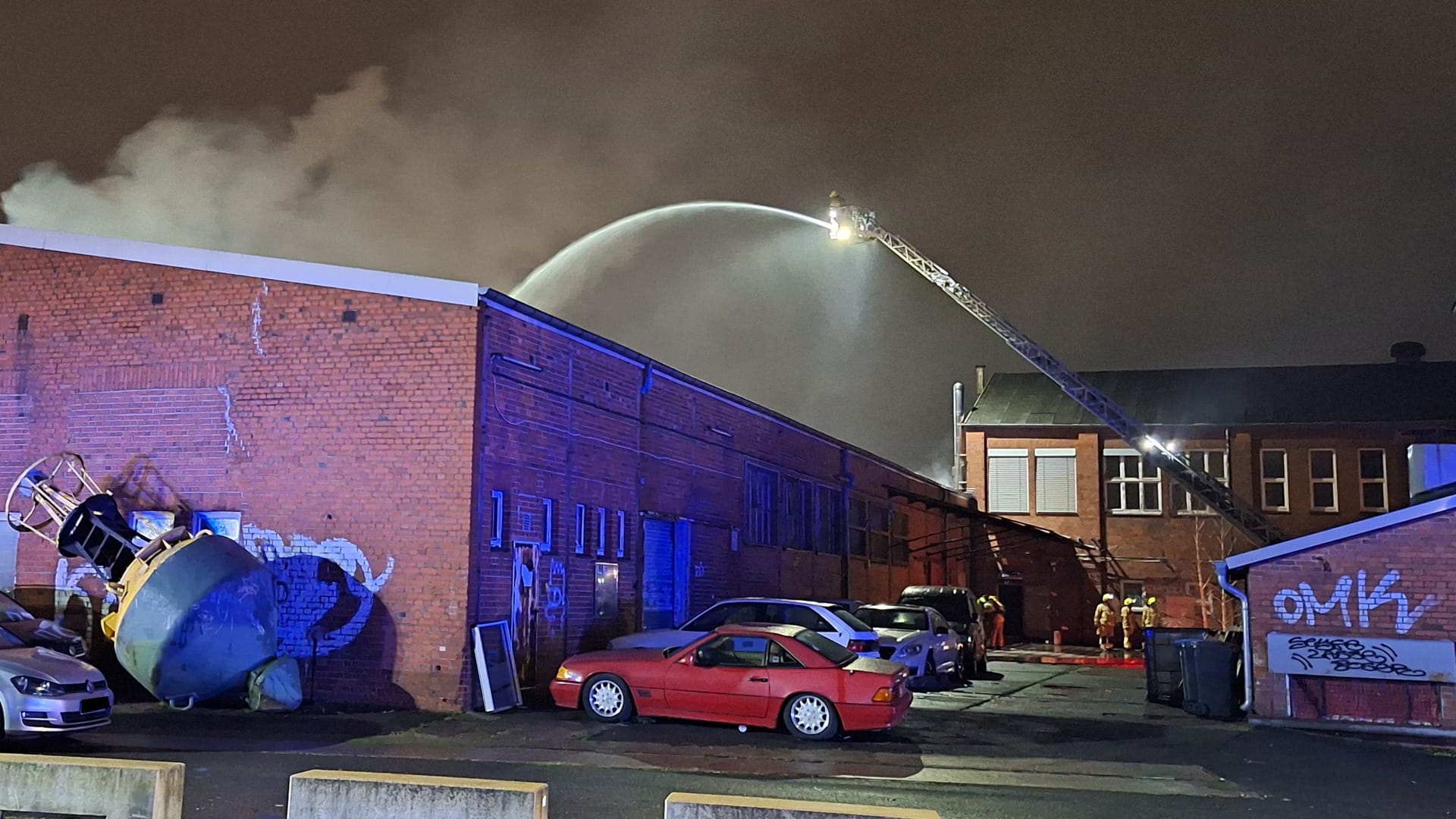 Flammen schlagen aus dem Dach einer Lagerhalle und Autowerkstatt.