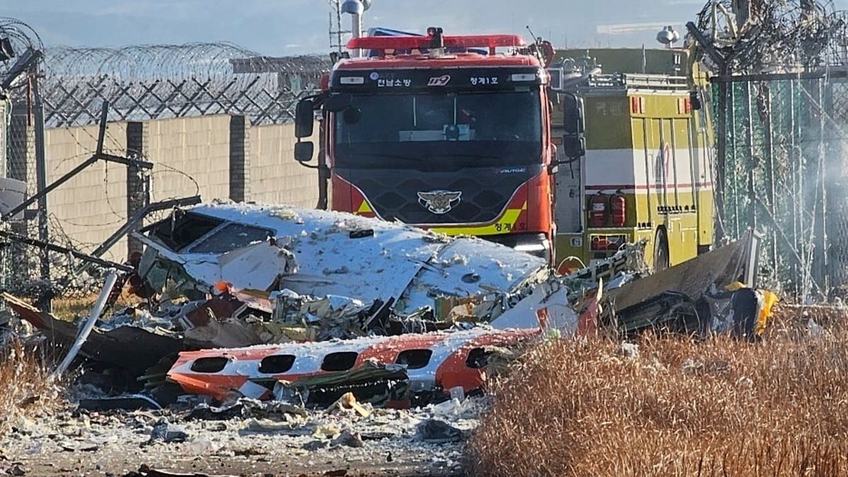 Ein Feuerwehrauto steht neben dem Wrack der zerstörten Maschine am Flughafen von Muan.