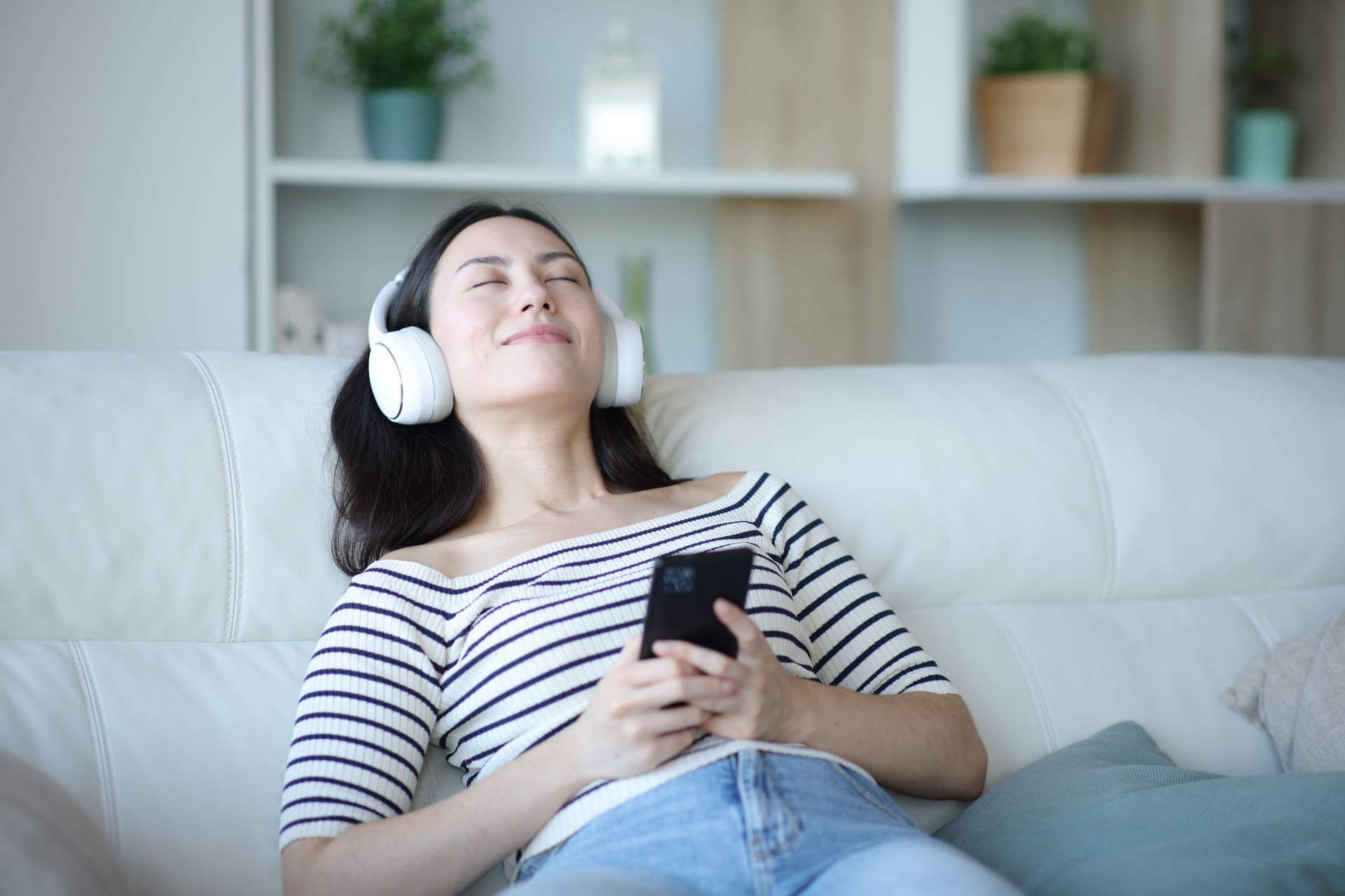 Eine Frau liegt auf der Couch und hört Musik: Songs von Taylor Swift streamten 2024 viele Menschen.