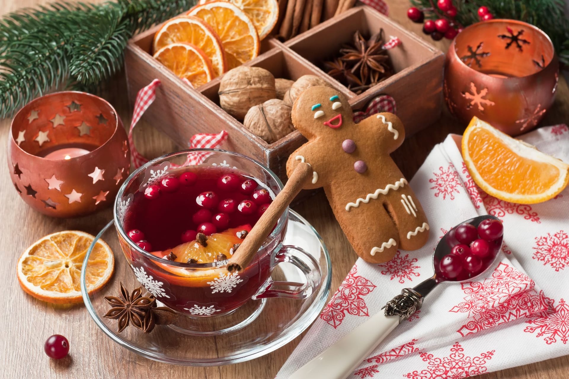 Weihnachtsgebäck auf einem mit Preiselbeeren, Zimt und getrockneten Orangen geschmückten Tisch