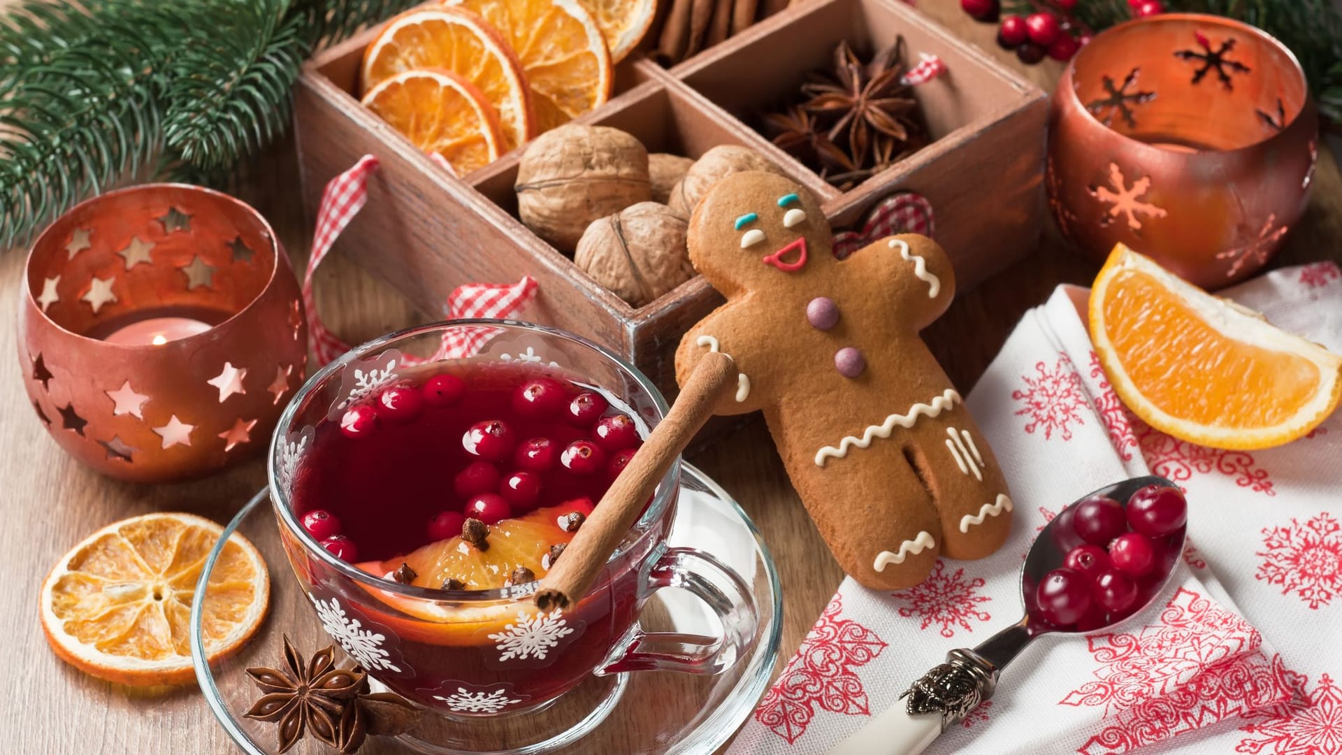 Weihnachtsgebäck auf einem mit Preiselbeeren, Zimt und getrockneten Orangen geschmückten Tisch