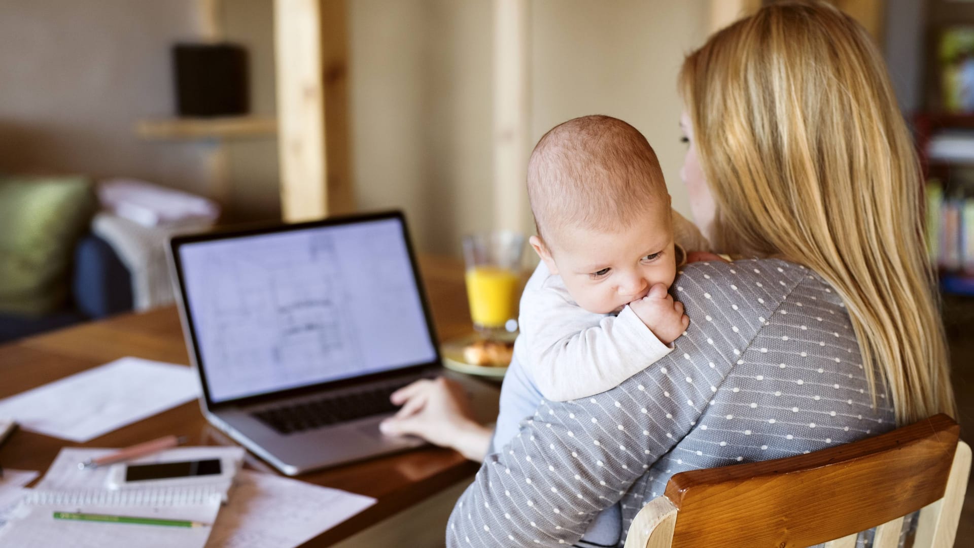 Eine Mutter sitzt mit ihrem Baby am Schreibtisch (Symbolbild): Die Wahl des Vornamens fällt Eltern oft nicht leicht.