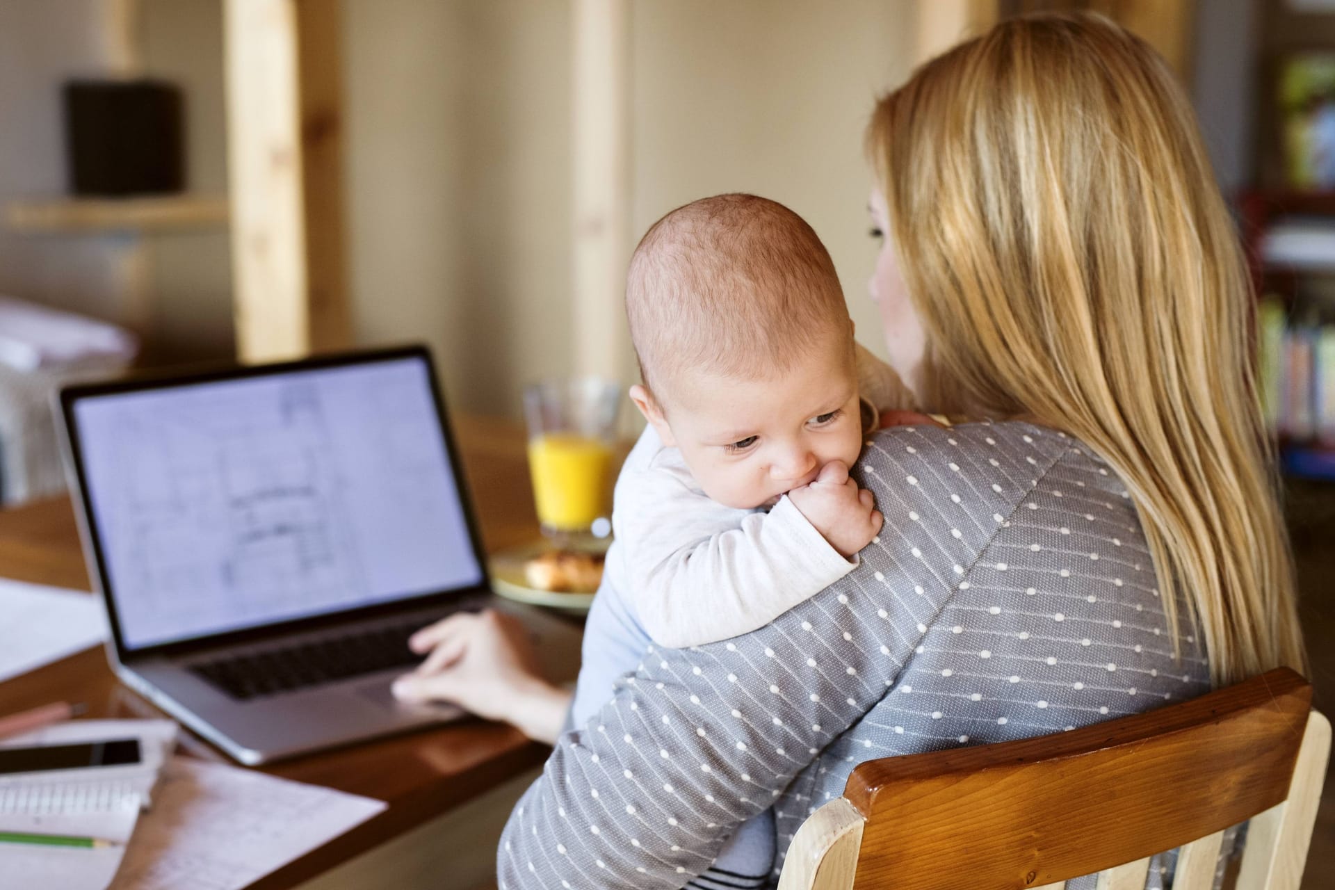 Eine Mutter sitzt mit ihrem Baby am Schreibtisch (Symbolbild): Die Wahl des Vornamens fällt Eltern oft nicht leicht.