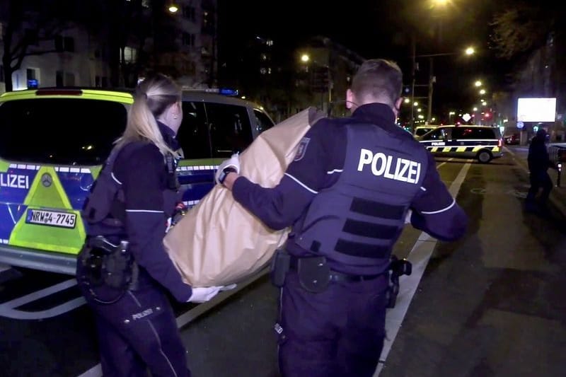 Polizeikräfte tragen den zurückgelassenen Koffer weg.