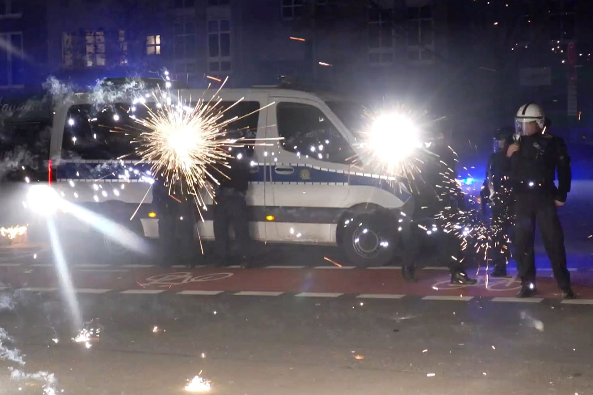 Einsatzkräfte in der Silvesternacht hinter explodierendem Feuerwerk (Archivbild): In der Nacht zu 2025 sind 3.000 Polizisten im Einsatz.