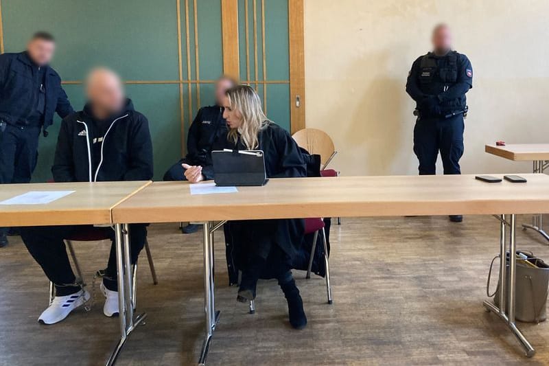 Der Angeklagte sitzt mit Fußfesseln neben seiner Verteidigerin in einem Saal der Stadthalle Verden: Die Staatsanwaltschaft wirft ihm Mord an seinen 27 Jahre alten Mitbewohner vor.