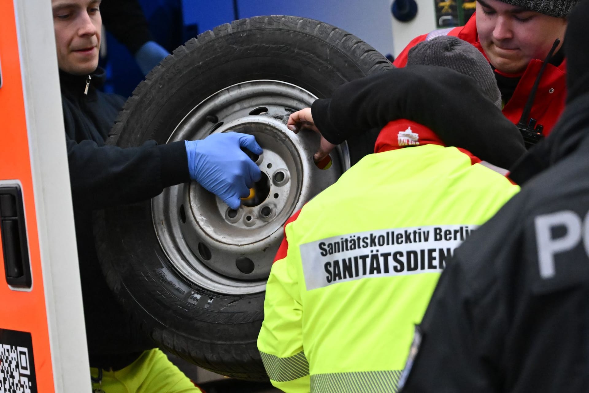 10.12.2024, Berlin: Eine Aktivistin, die sich an einem Reifen festgeklebt hat, wird während Demonstrationen gegen den "World LNG Summit" der Gasindustrie und Flüssiggasanbieter in Berlin in einen Rettungswagen gebracht. Der Gasenergiegipfel findet vom 9. bis 12. Dezember im Hotel Adlon statt.