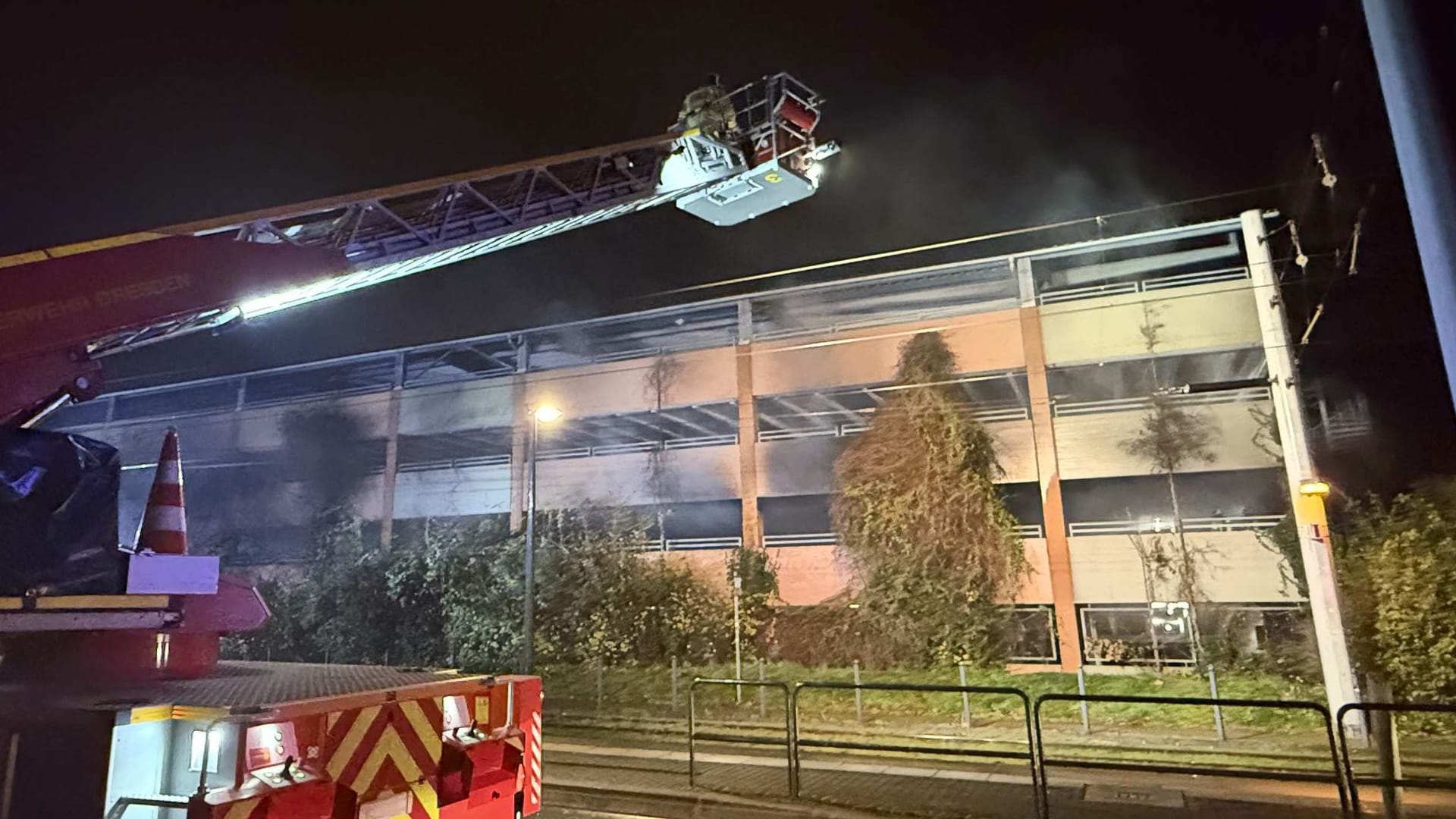 Feuerwehrleute auf einer Drehleiter arbeiten an einem Brand in einem Parkhaus: Ein Auto ist in einem Dresdner Parkhaus komplett ausgebrannt.