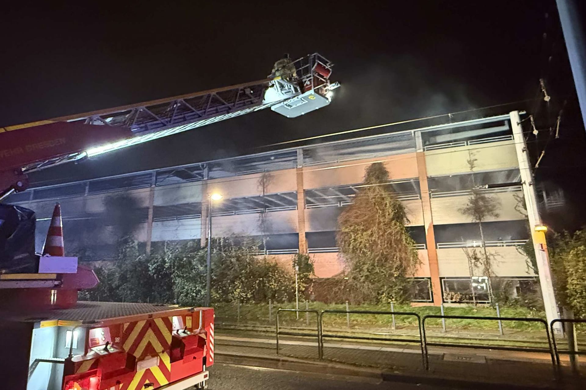 Feuerwehrleute auf einer Drehleiter arbeiten an einem Brand in einem Parkhaus: Ein Auto ist in einem Dresdner Parkhaus komplett ausgebrannt.