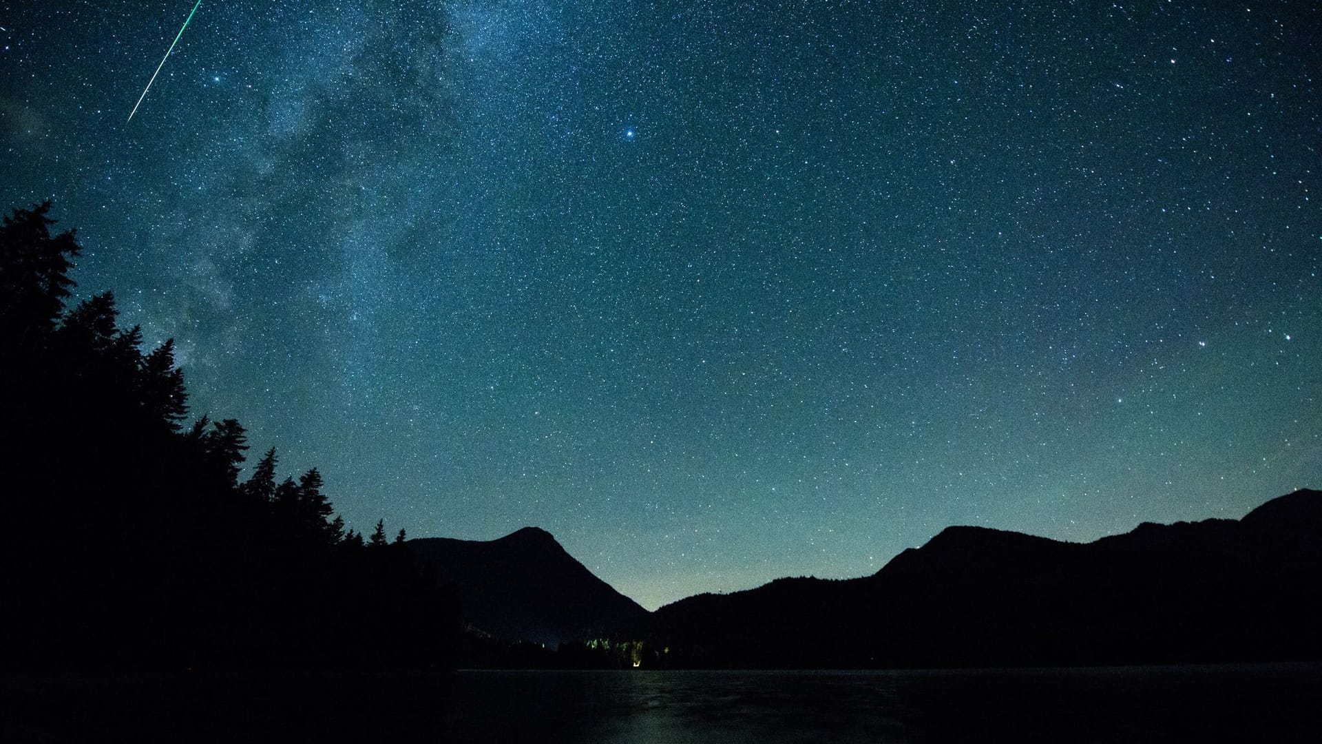 Eine Sternschnuppe leuchtet am Himmel über dem Walchense (Bayern)