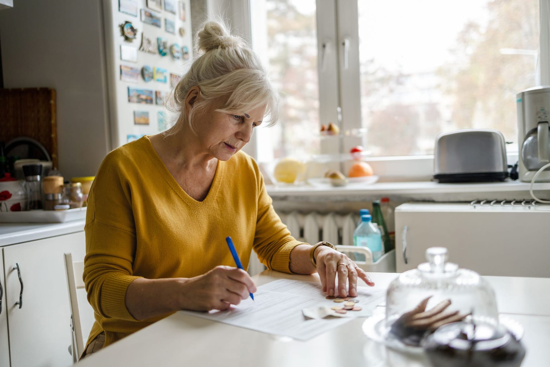 Rentnerin beugt sich über Dokumente: Der steigende Pflegebeitrag führt im neuen Jahr zu einer Besonderheit.