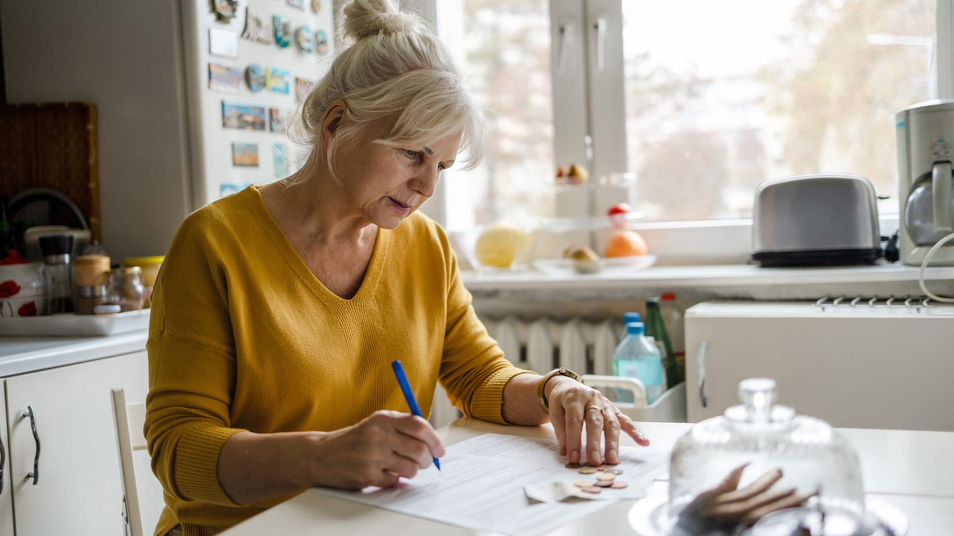 Rentnerin beugt sich über Dokumente: Der steigende Pflegebeitrag führt im neuen Jahr zu einer Besonderheit.